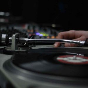 The dj uses vinyl records to mix electronic music and beat rap